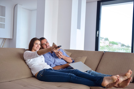 Couple on sofa with TV remoteの写真素材