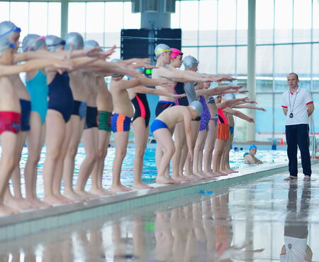group of happy kids children   at swimming pool class  learning to swim