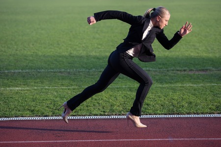 business woman in start position ready to run and sprint on athletics racing trackの写真素材