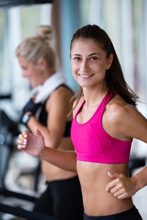 Beautiful group of young women friends  exercising on a treadmill at the bright modern gymの写真素材