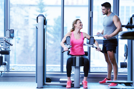 Gym woman exercising with her personal trainerの写真素材