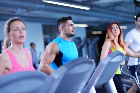 group of young people running on treadmills in modern sport  gym