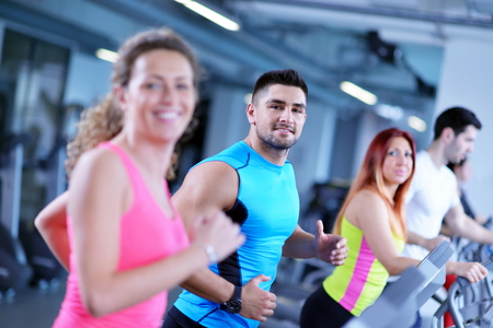 group of young people running on treadmills in modern sport  gym