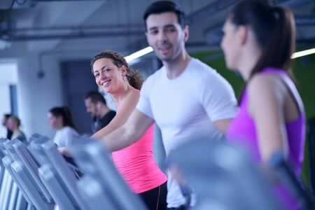group of young people running on treadmills in modern sport  gymの写真素材