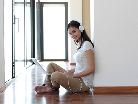 beautiful young woman relax and work on laptop computer modern  home office while listening musin on white headphonesの写真素材