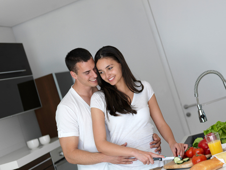 happy young couple have fun in modern kitchen indoor while preparing fresh fruits and vegetables food saladの写真素材