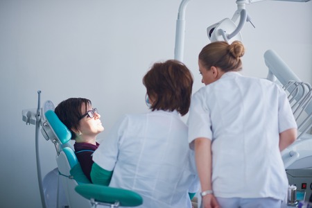 Closeup of a woman patient at the dentist waiting to be checked up with the woman doctor in the backgroundの写真素材