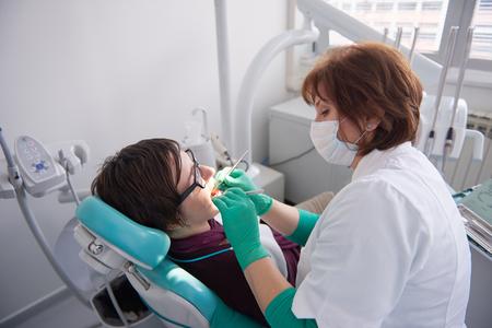 Closeup of a woman patient at the dentist waiting to be checked up with the woman doctor in the backgroundの写真素材