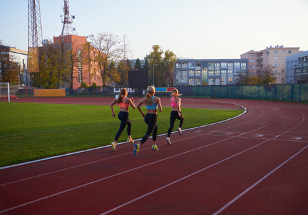 athlete woman group  running on athletics race track on soccer stadium and representing competition and leadership concept in sportの写真素材