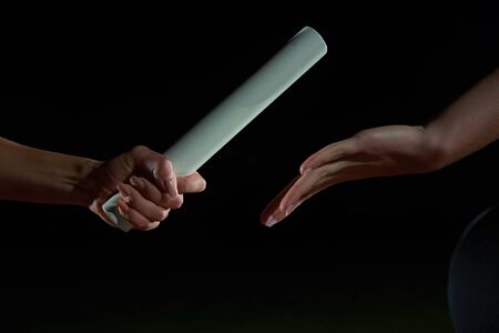 Woman athletic runners passing baton in relay raceの写真素材