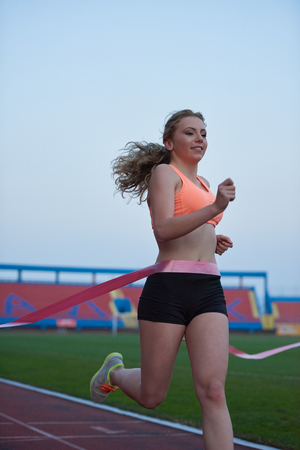 young runner sporty woman relaxing and stretching on athletic race trackの写真素材