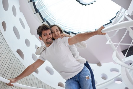 relaxed young couple on spiral glass stairs in modern home villa indoors