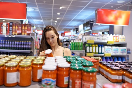 young woman shopping for fruits and vegetables in produce department of a grocery store supermarket
