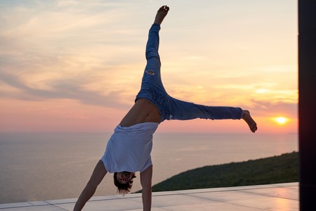 handsome young man relaxing and working on laptop computer at home balcony while looking sunsetの写真素材