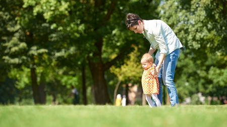happy mother and baby child in park making first steps .  Walking and hugging.の写真素材