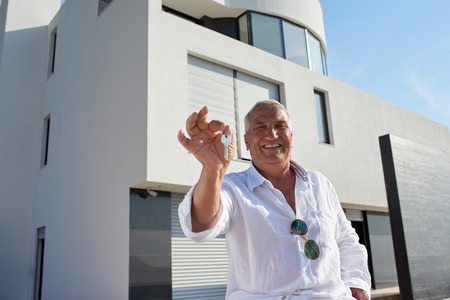 senior man in front of luxury modern home villaの写真素材