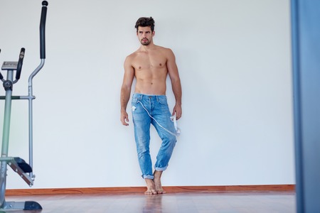 handsome young man listening music on headphones at modern home over  white wall and standing on handsの写真素材