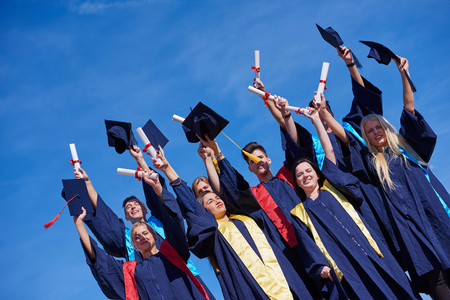 high school students graduates tossing up hats over blue sky.の写真素材