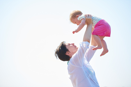 happy mom and baby on beach  have fun while learning to walk and  make first stepsの写真素材
