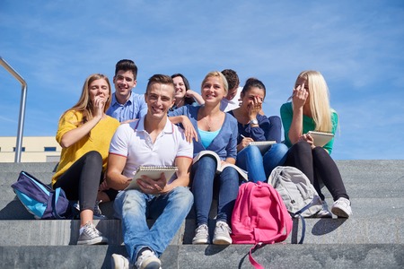 Group portrait  of happy  students outside sitting on steps have funの写真素材