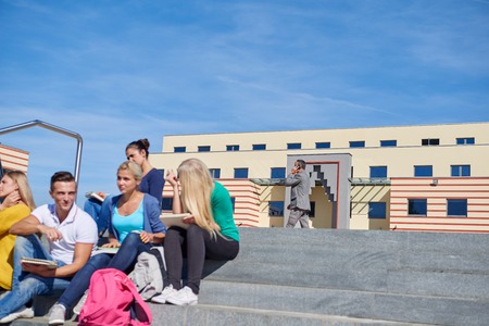 Group portrait  of happy  students outside sitting on steps have funの写真素材