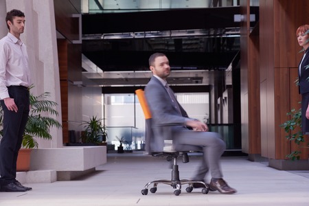 business man sitting in office chair,  people group  passing by: Concept of time, rush, organizationの写真素材