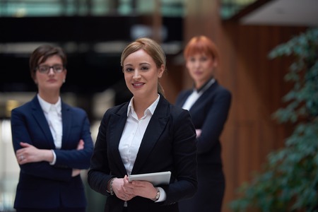 young business woman group,  team standing in modern bright office and working on tablet computerの写真素材