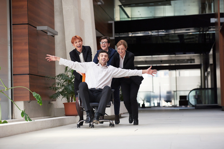 business people group at modern office indoors have fun and push office chair on corridorの写真素材