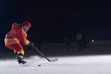 teen girl children ice hockey player in action kicking puck with stickの写真素材