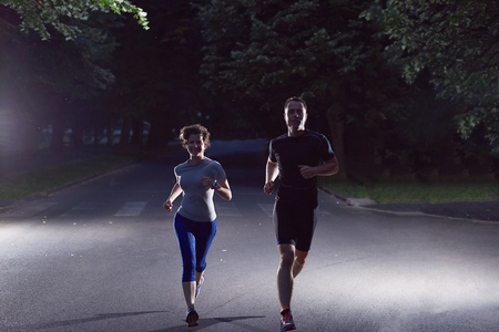 urban sports, healthy couple jogging in the city at early morning in nightの写真素材