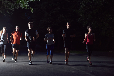 people group jogging at night, runners team on early morning  trainingの写真素材