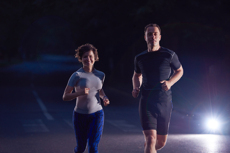 urban sports, healthy couple jogging in the city at early morning in nightの写真素材