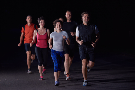people group jogging at night, runners team on early morning  trainingの写真素材