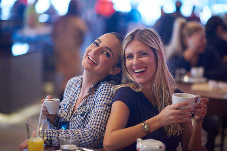 happy girl friends have cup of coffee in modern city restaurantの写真素材