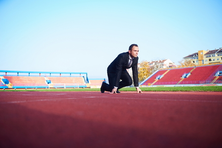 business man in start position ready to run and sprint on athletics racing trackの写真素材