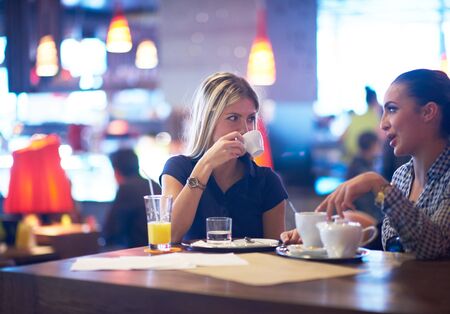 happy girl friends have cup of coffee in modern city restaurantの写真素材