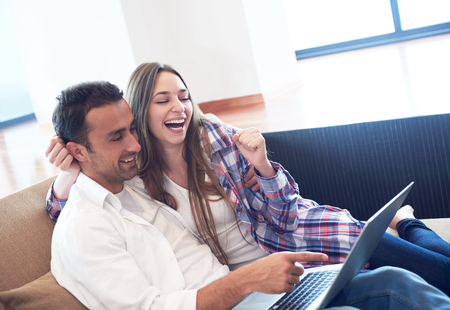happy young relaxed  couple working on laptop computer at modern home interiorの写真素材