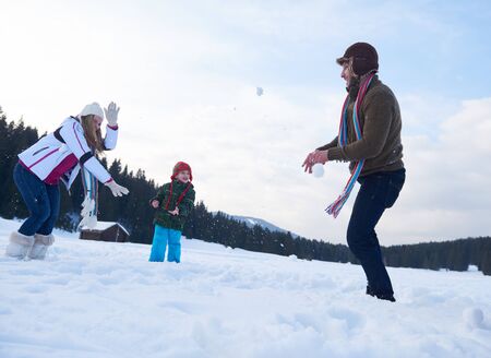 happy young  family playing in fresh snow  at beautiful sunny winter day outdoor in natureの写真素材