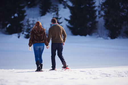 happy young  couple having fun and walking in snow shoes. Romantic winter relaxation sceneの写真素材