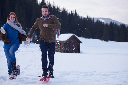 happy young  couple having fun and walking in snow shoes. Romantic winter relaxation sceneの写真素材