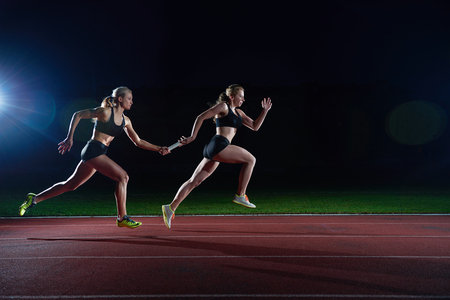 woman athletic runners passing baton in relay raceの素材 [FY31051226225]