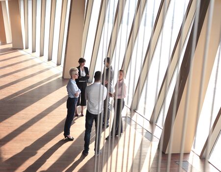 business people group standing together as team by window  in modern bright office interior
