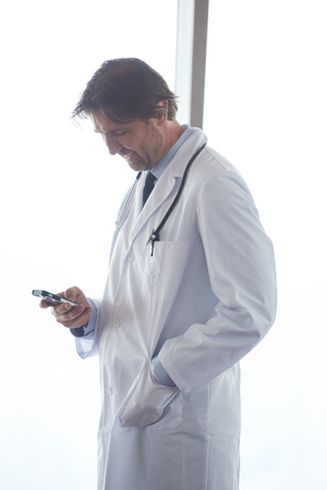 handsome doctor speaking on cellphone at modern hospital indoorsの写真素材