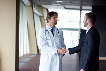 doctor handshake with a patient at doctors bright modern office in hospitalの写真素材