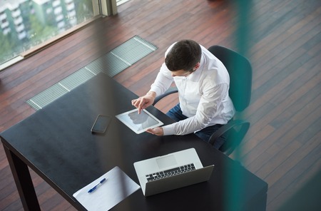 top view of happy young business man,  work tablet and laptop and relax at modern bright office interior, successful hipster with beard at workplaceの写真素材