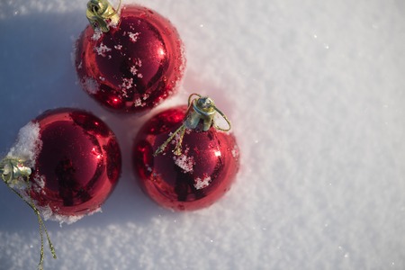 christmas red balls decoration in fresh snow background on beautiful sunny winter dayの写真素材
