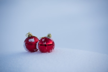 christmas red balls decoration in fresh snow background on beautiful sunny winter dayの写真素材