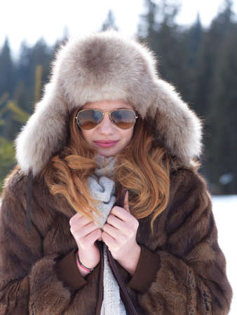 portrait of beautiful young redhair woman in snow scenery with warm hat
