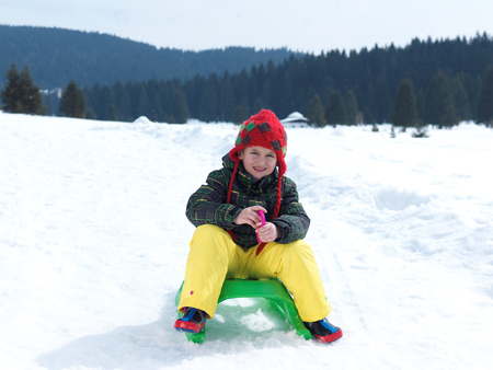 happy young boy have fun on winter vacatioin, sledding children on fresh snow at sunny day outdoor...