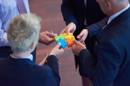 business people group assembling jigsaw puzzle and represent team support and help concept, top view perspective at modern bright office interiorの写真素材